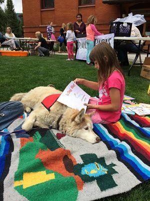 child reading to a therapy dog on the south branch library lawn