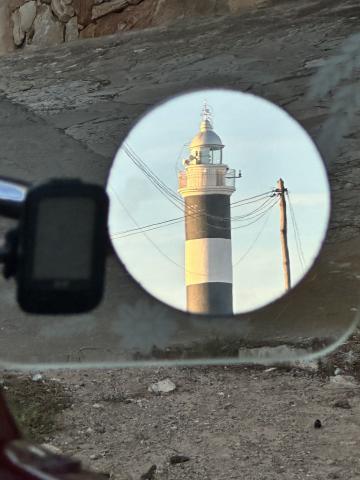 photo of a light house in spain in the rear view mirror of a car